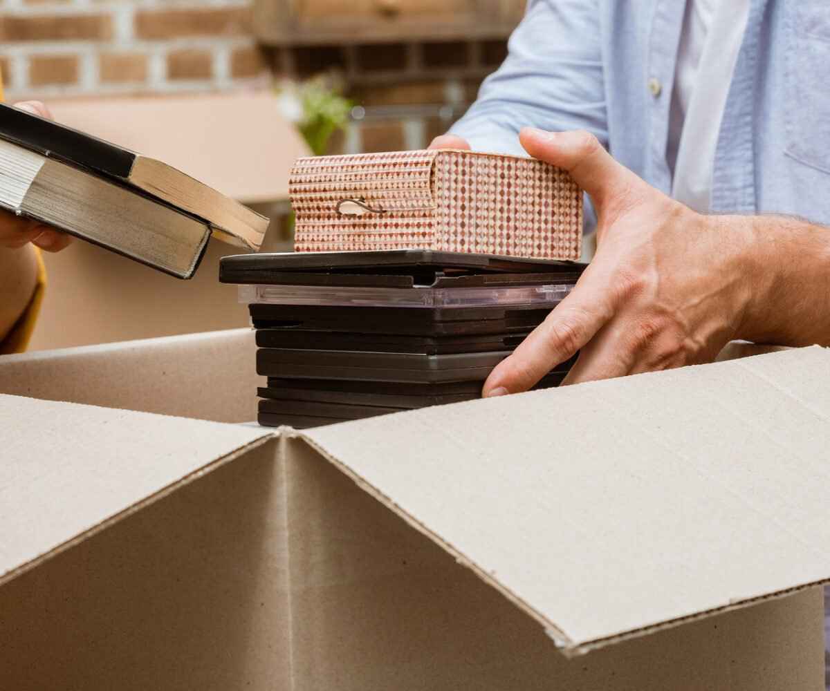 Person unloading a stack of DVDs out of a moving box.