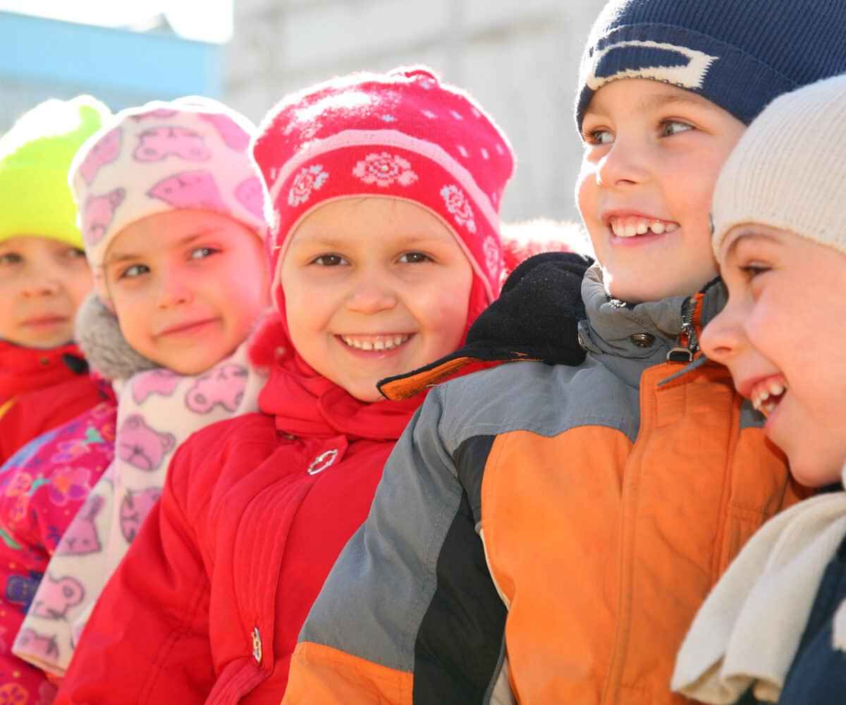 Five young children in winter coats smiling.
