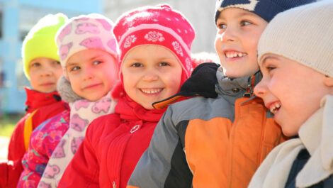 Five young children in winter coats smiling.