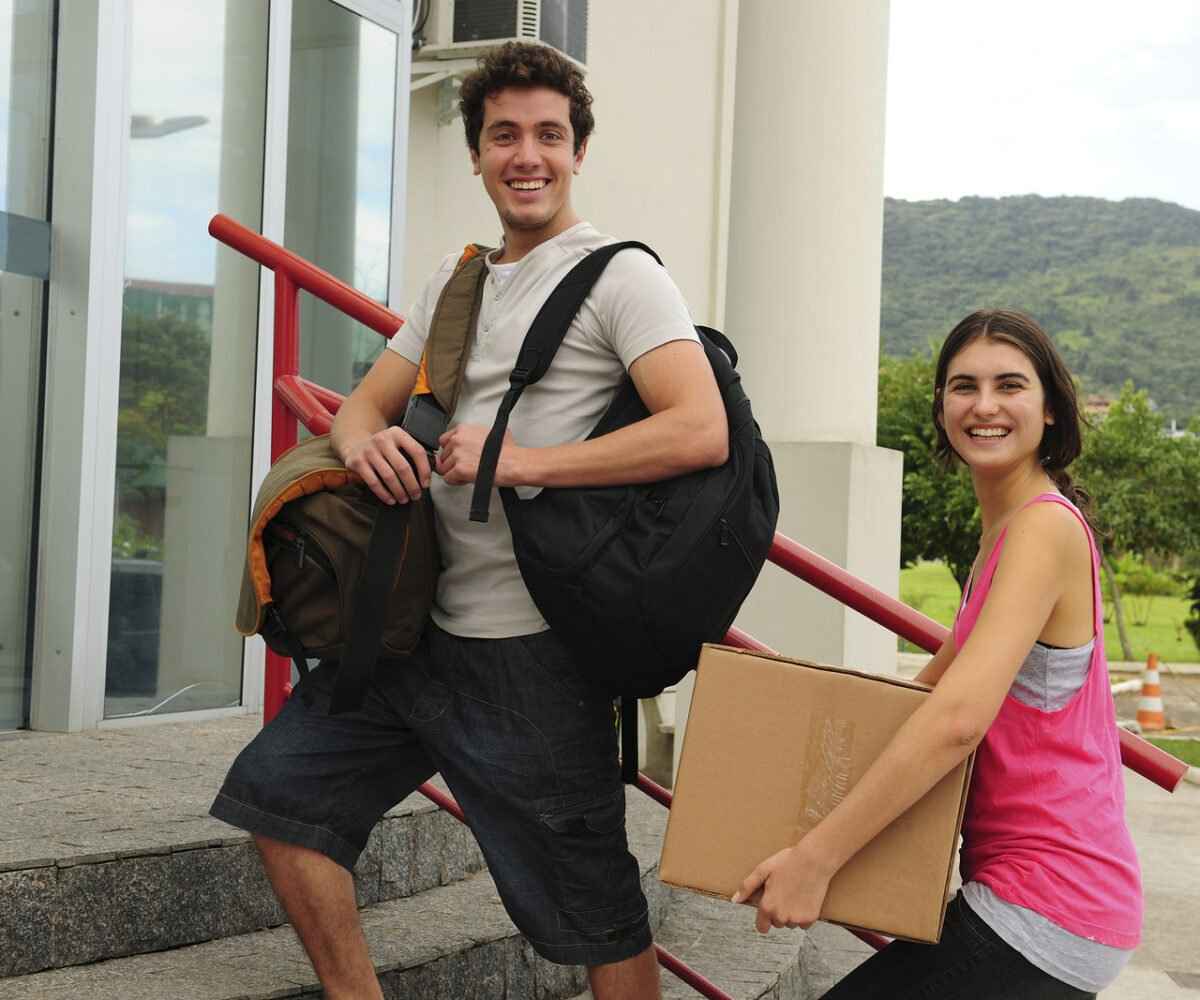 Young sister helping her brother move into freshman year dorm on college move-in day