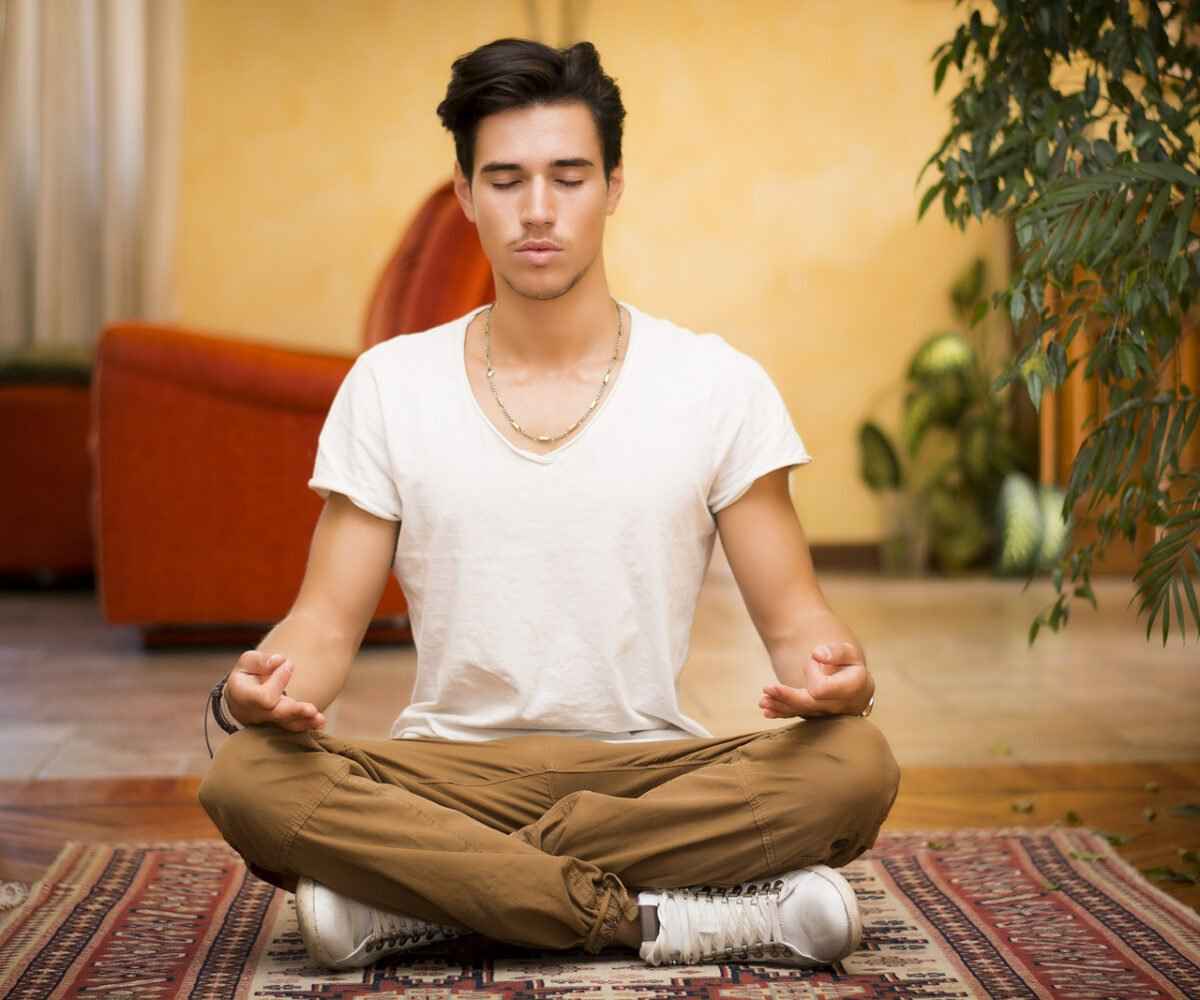 A young man meditates on his floor in his feng shui home.