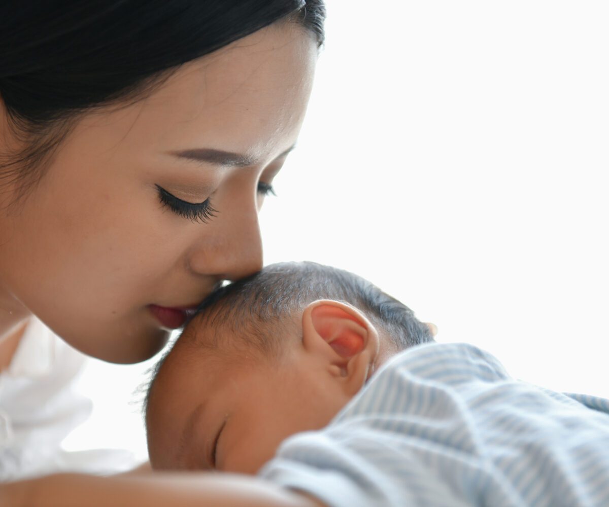 Young mother kissing her newborn baby's head.