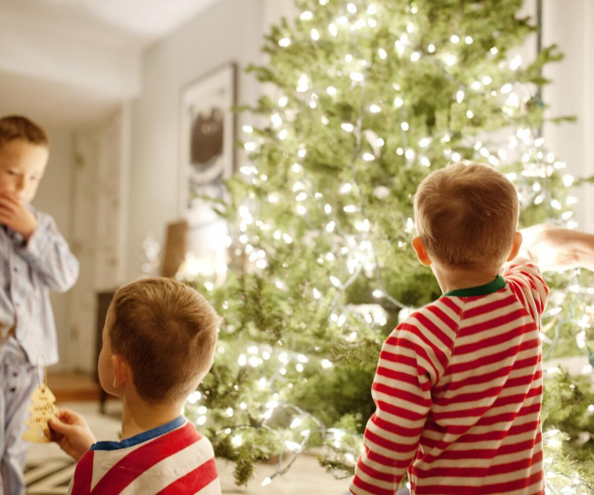 Three young brothers decorating a Christmas tree.