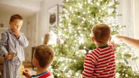 Three young brothers decorating a Christmas tree.