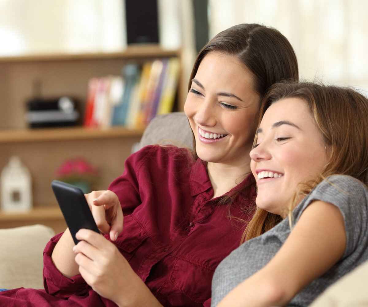 Two young females looking at a phone laughing.