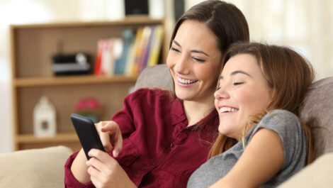 Two young females looking at a phone laughing.