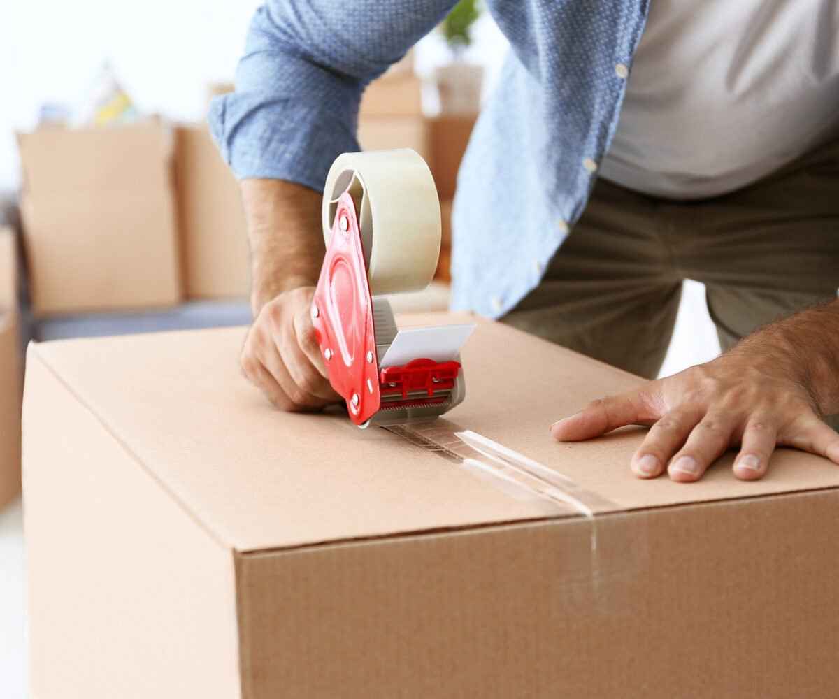 A man taping a moving box.