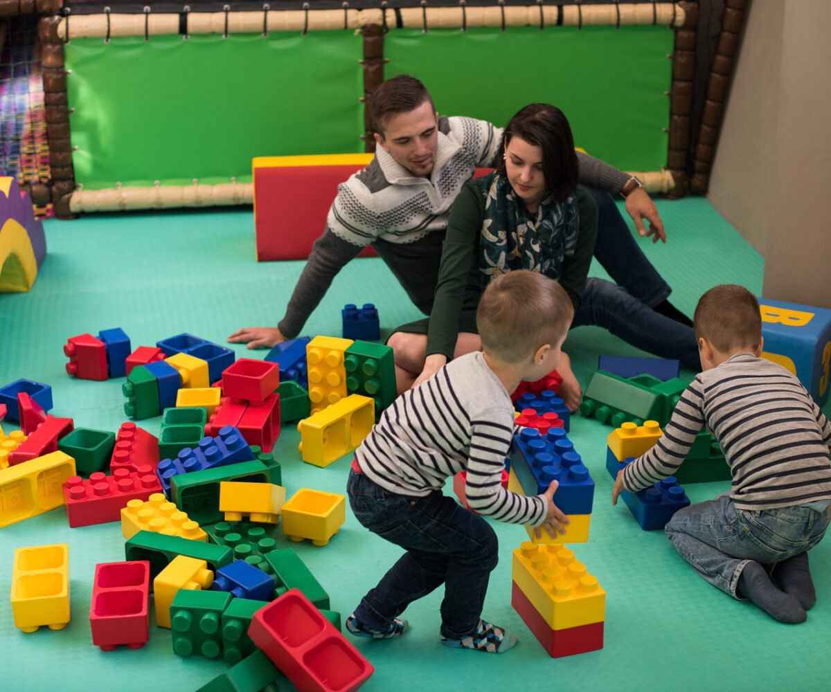 A young family playing with giant lego pieces.