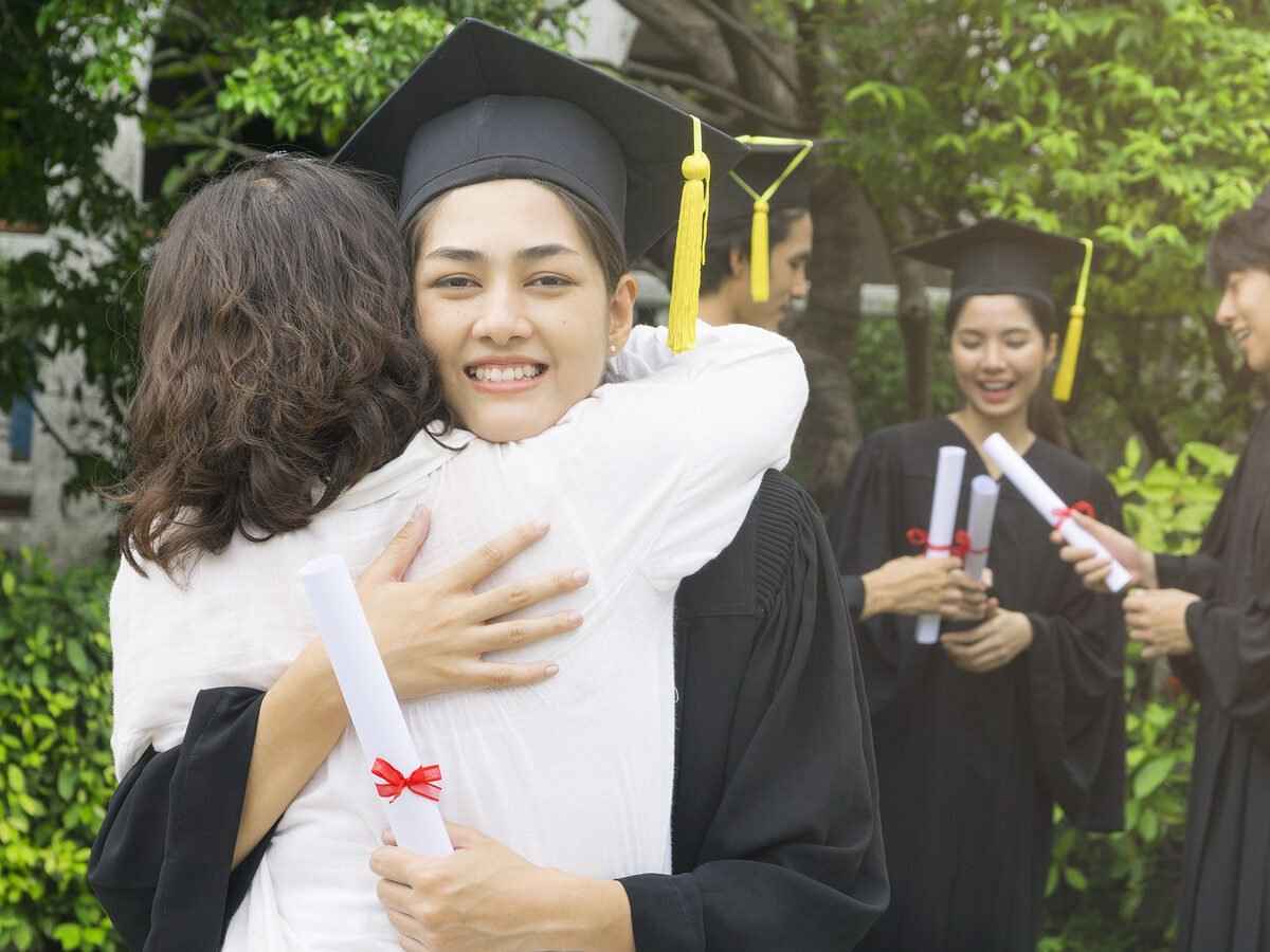 Parent hugging child after graduating from college.