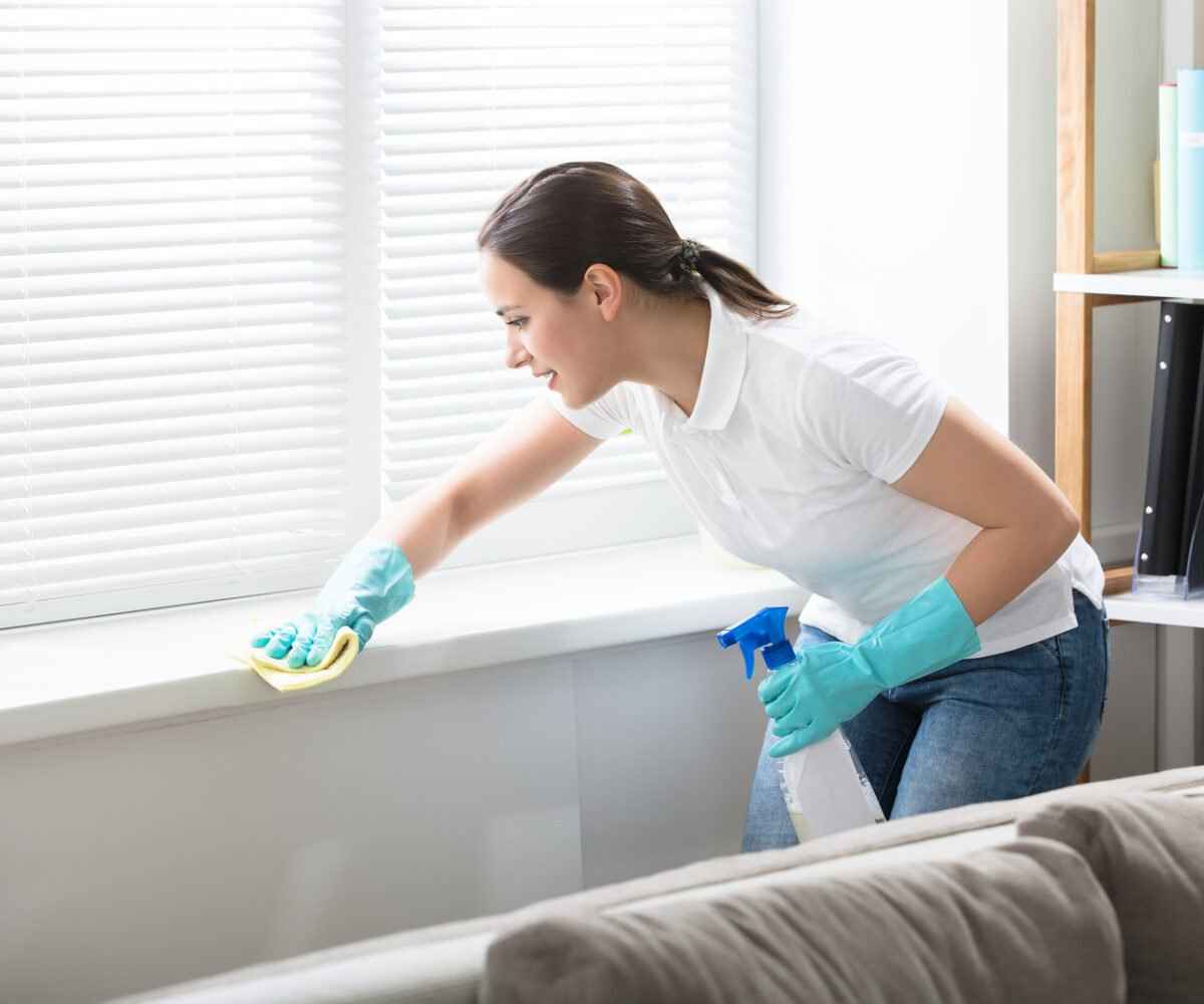 A woman dusting a windowsill.