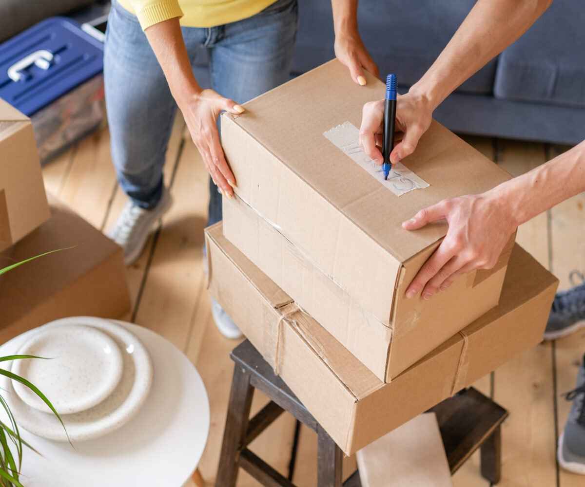 Two people labeling moving boxes.