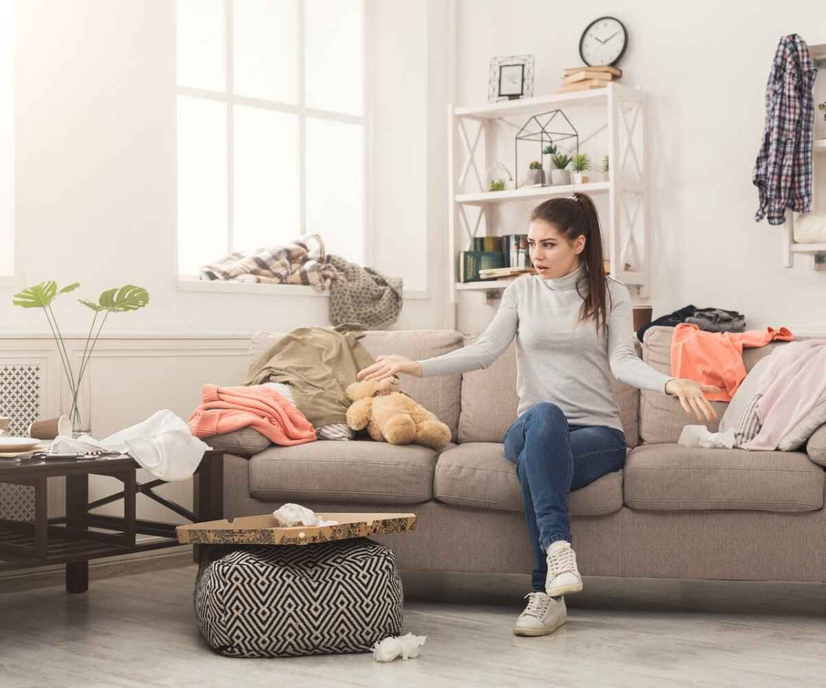 A stressed out woman looking at the mess on her floor.