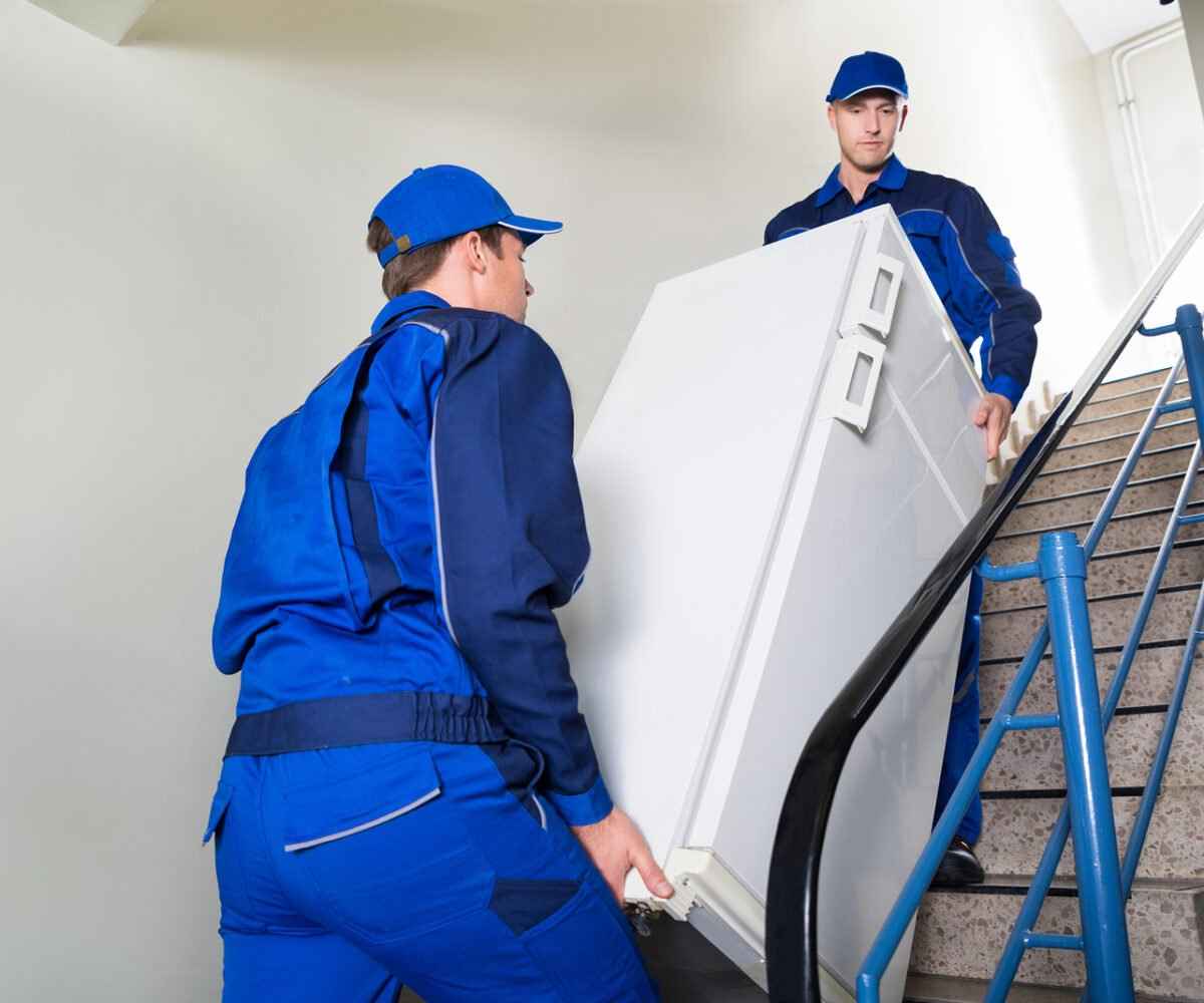 Two men moving a refrigerator up a flight of stairs.