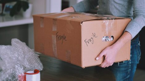 Man carrying a fragile box into a house.