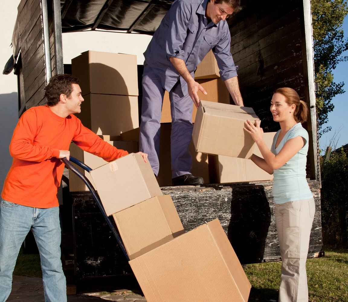 Three people carrying boxes out of a moving truck.