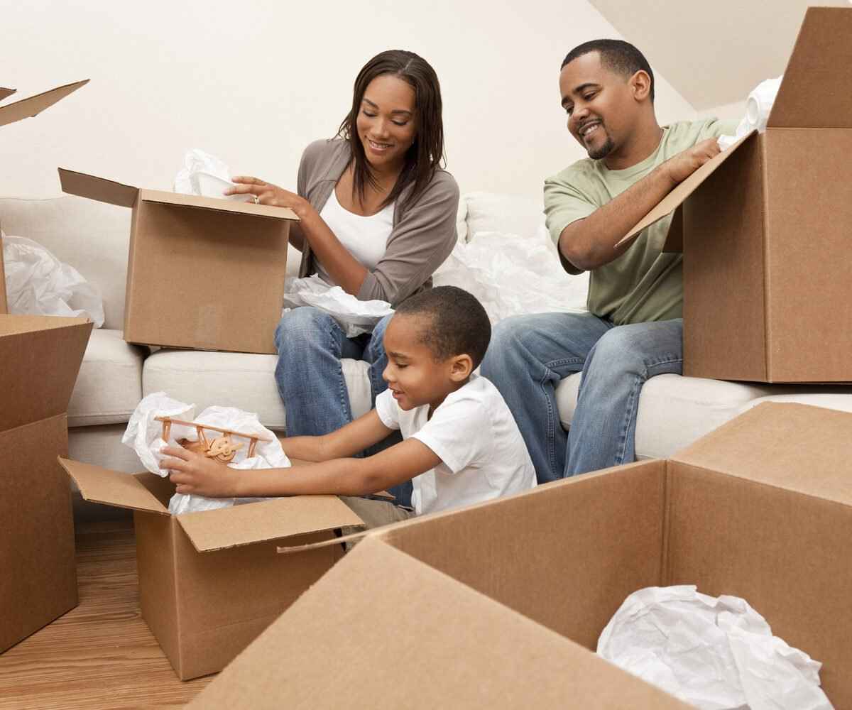 Family of three unpacking moving boxes.