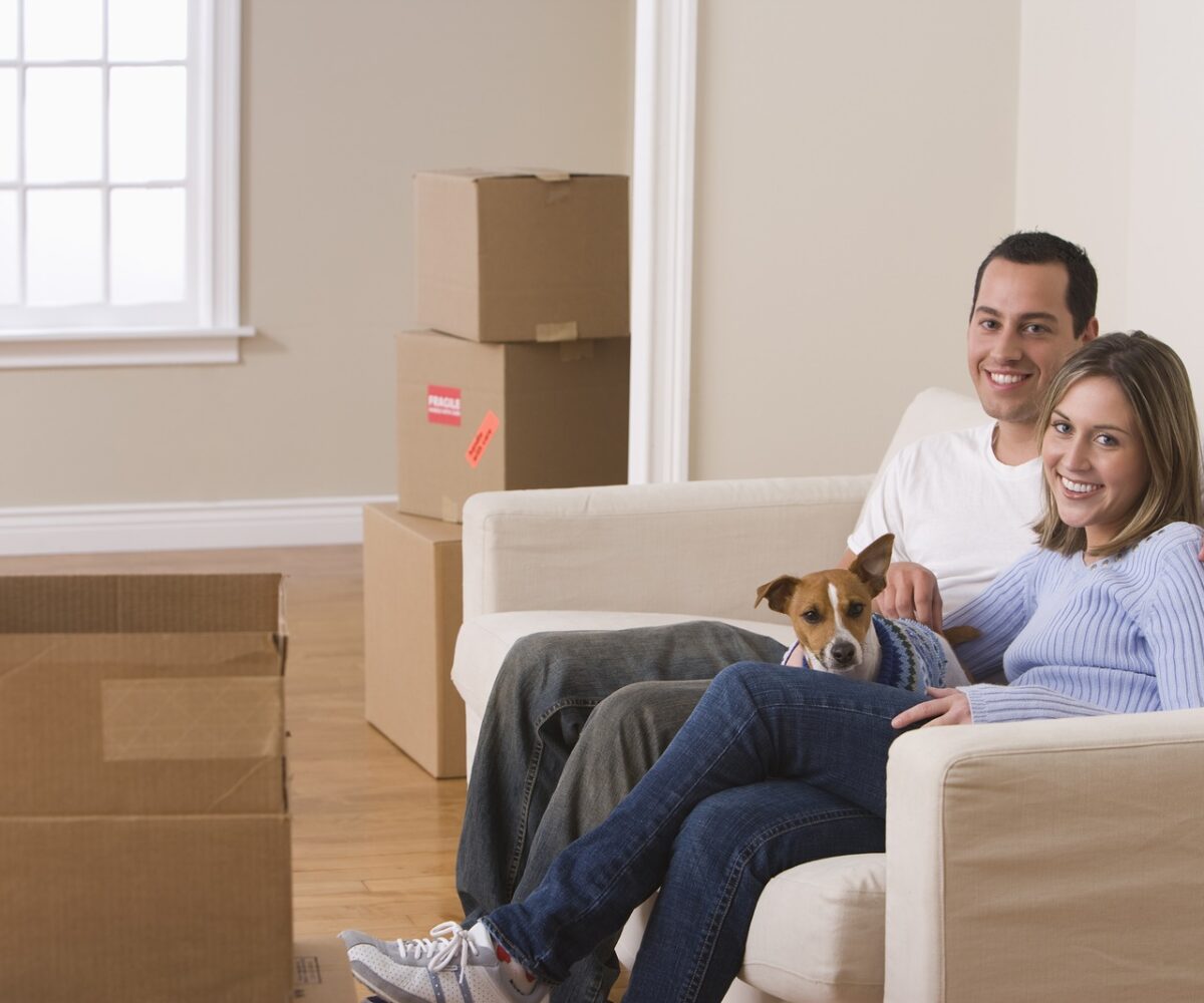 Young couple and their dog sitting on a couch.