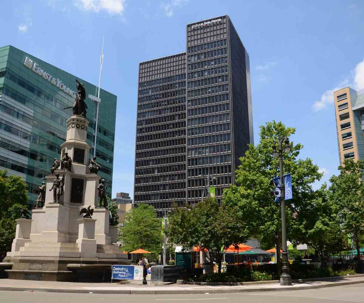 A statue and large buildings in Campus Martius Park in Detroit.