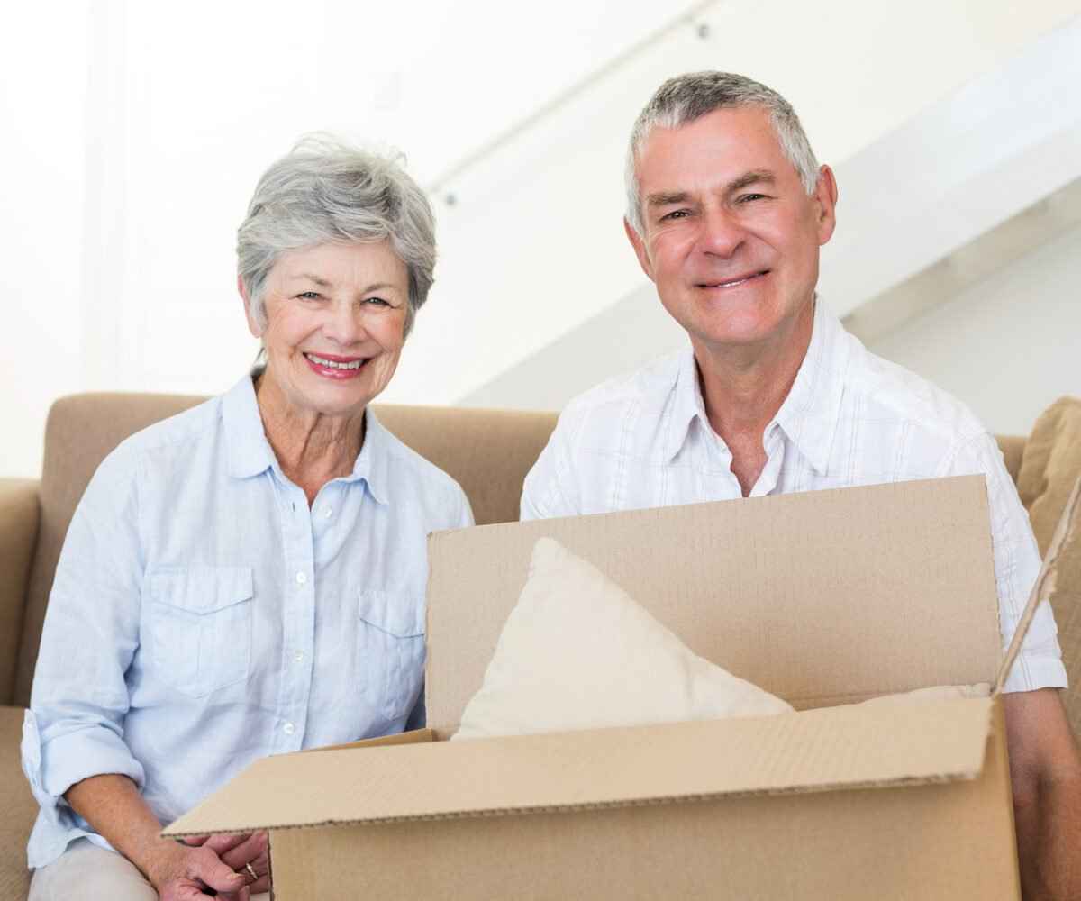 Cheerful elderly couple holding a moving box.