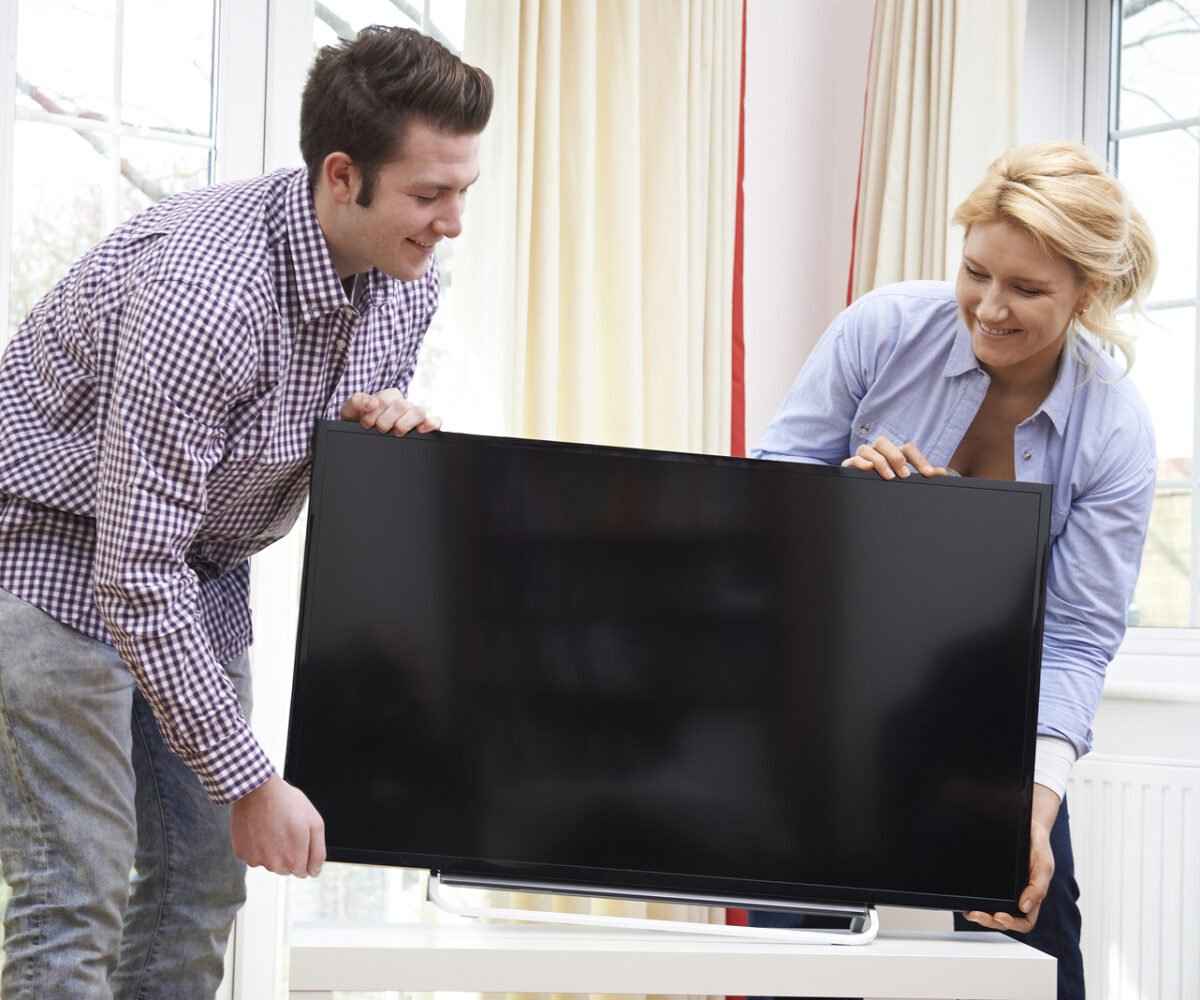 Young couple moving a television.