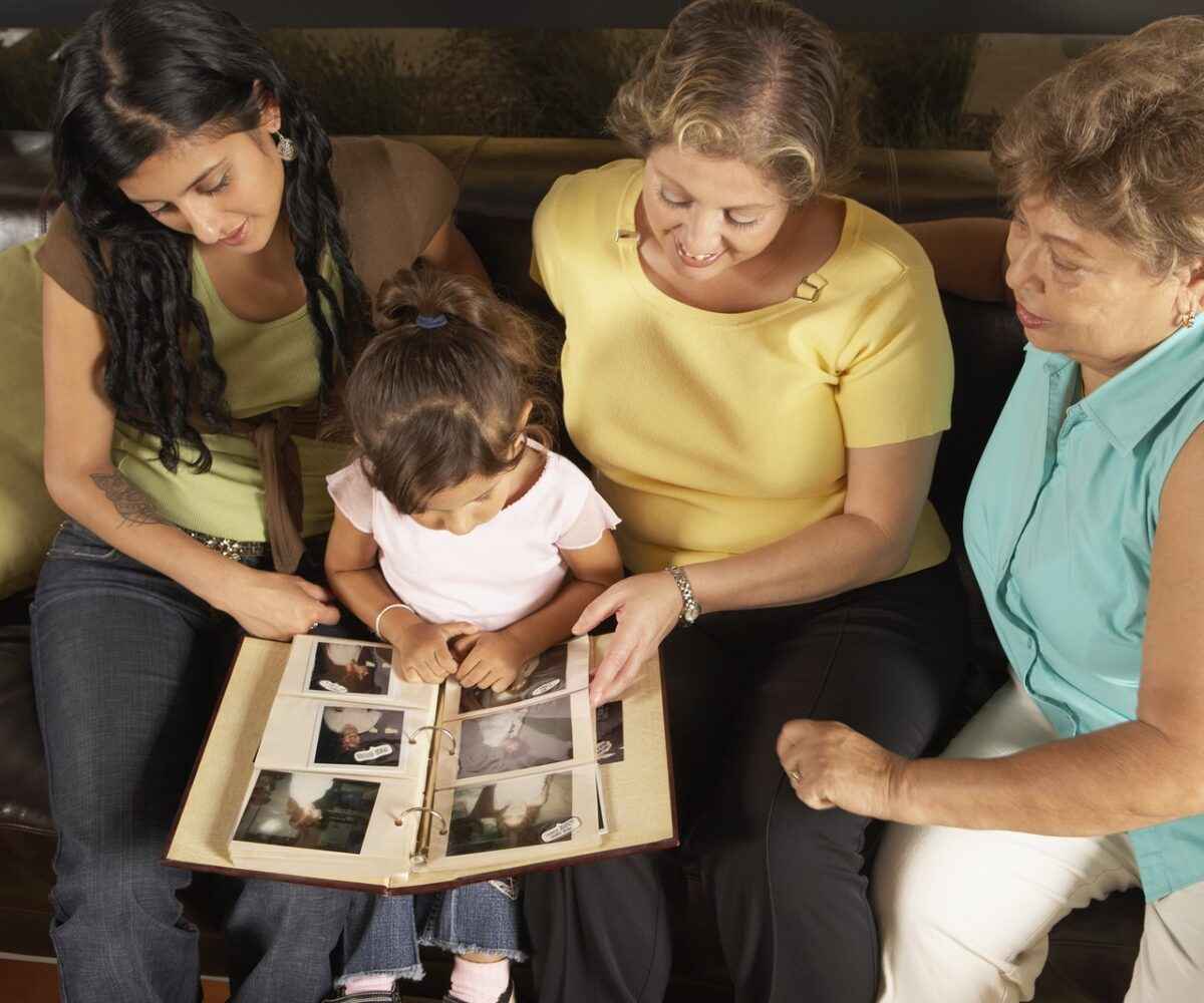 Three woman and a child looking at a family photo album.