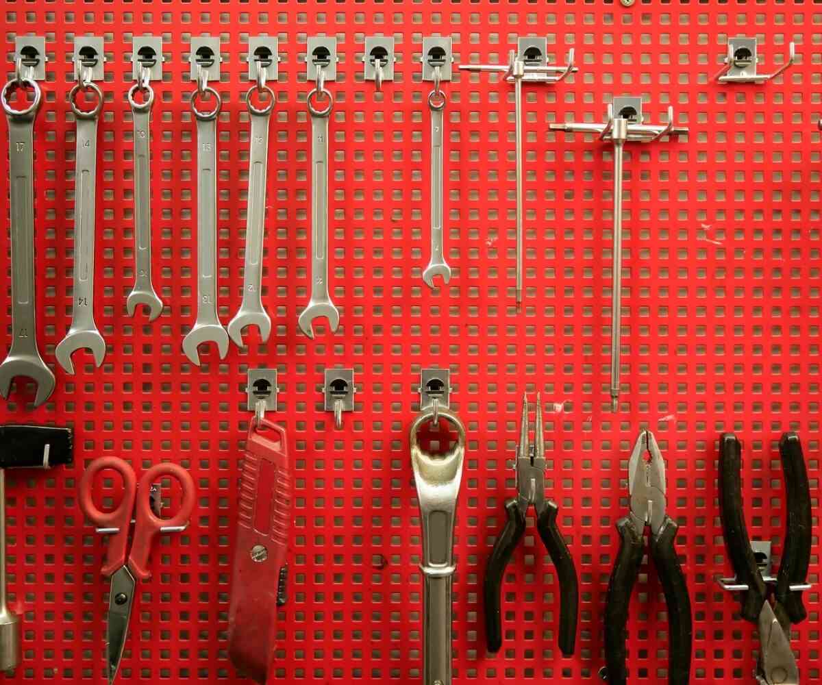 Handtools hanging on a red peg board.