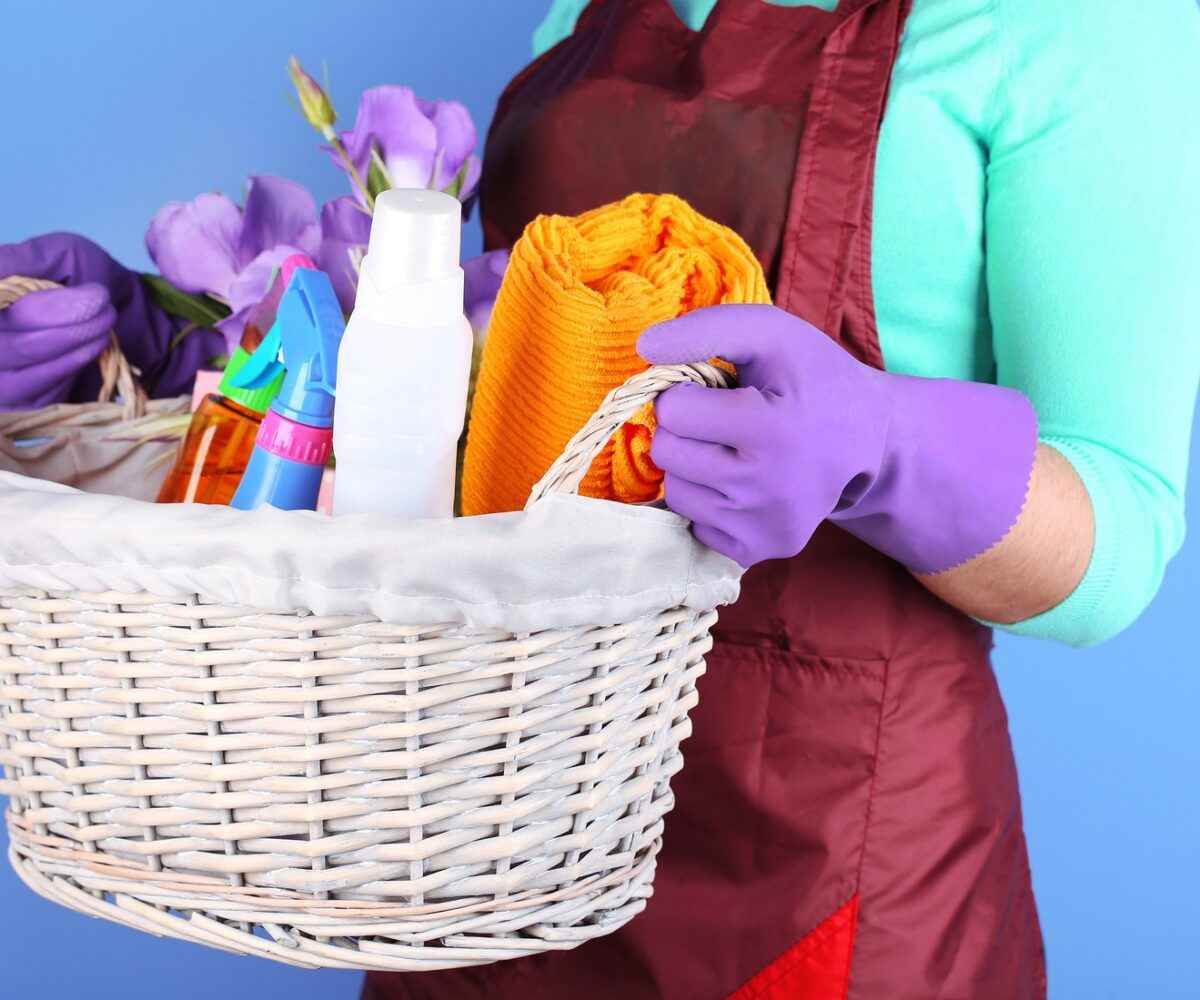 Cleaning lady carrying basket of cleaning supplies.