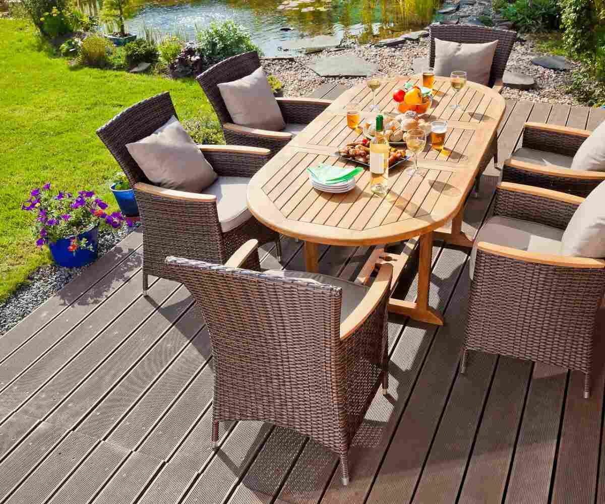 Patio table with food and drinks on it in a backyard.