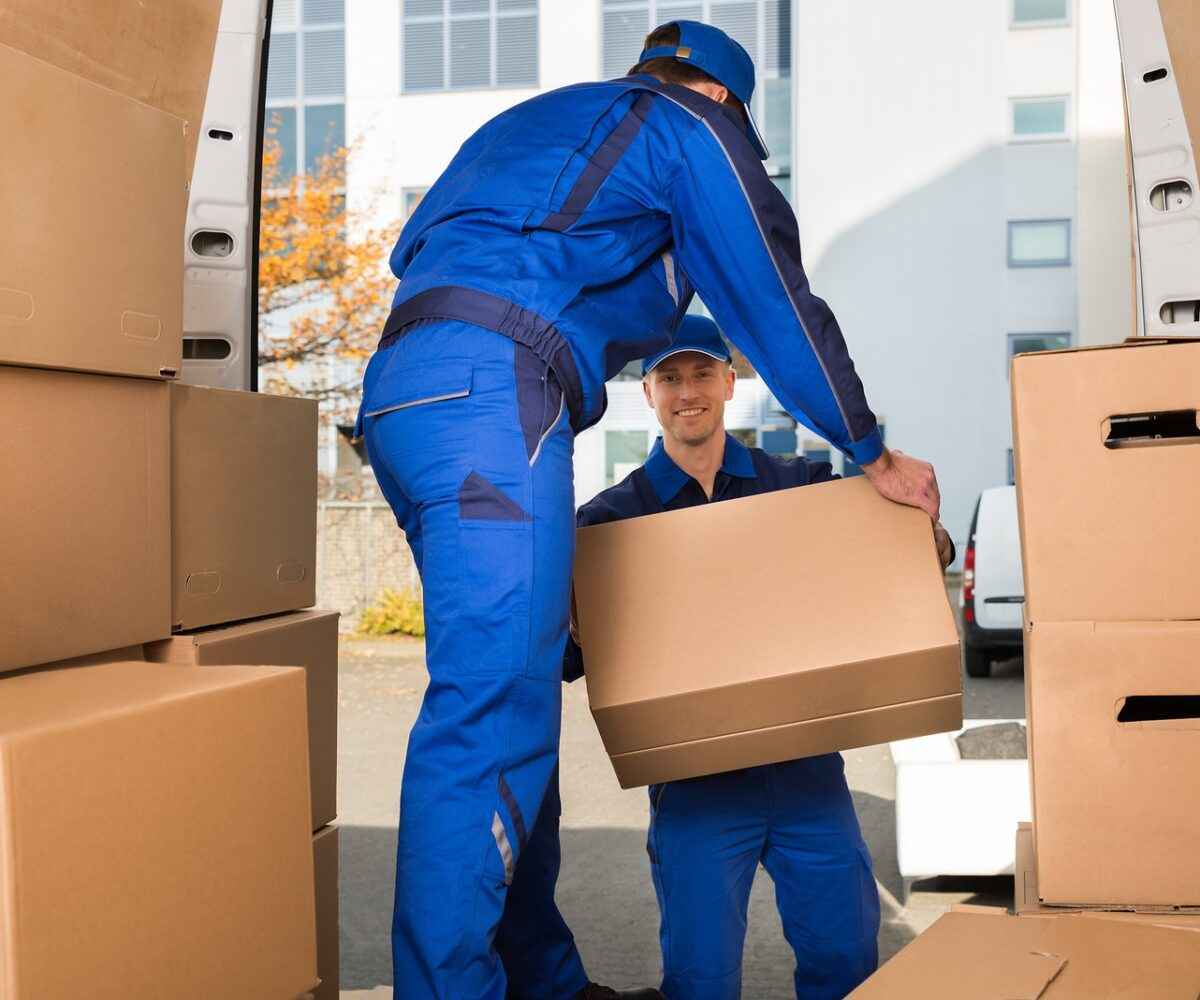 Two men moving boxes out of a moving van.
