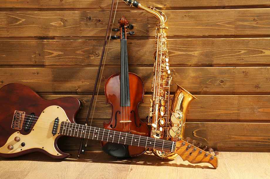 Guitar, violin, and saxophone leaning against a wall.