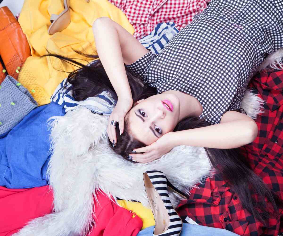 Young adult female laying on a pile of clothes.