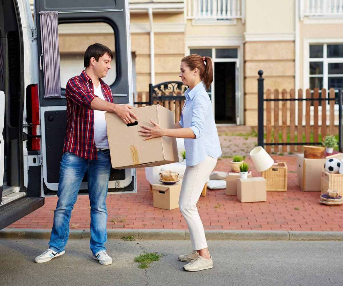 Man passing a moving box to woman from a van.