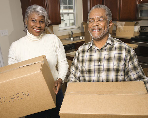 Middle aged couple carrying moving boxes.