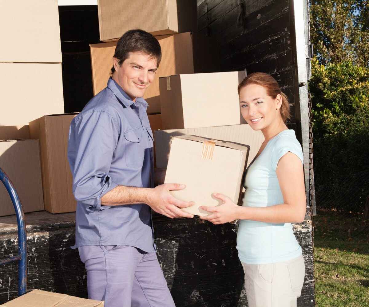 Young smiling couple moving boxes out of a truck.
