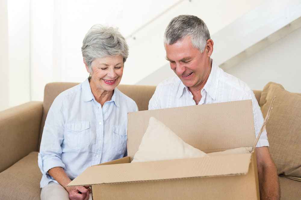 Elderly couple smiling opening a box.