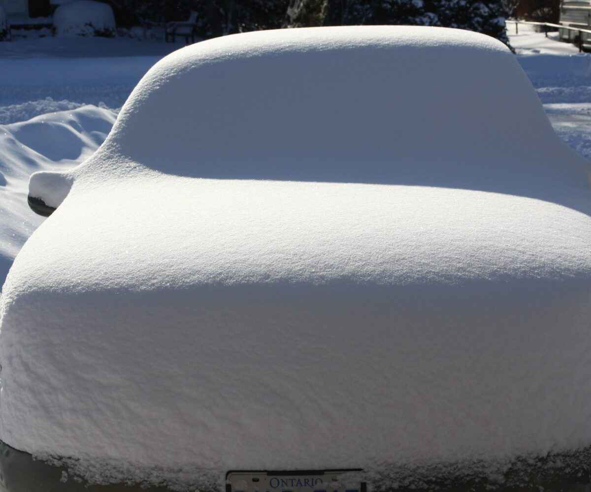 Car with Ontario license plate covered in snow.