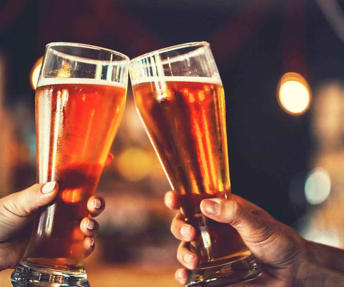 Two people toasting with beer glasses.
