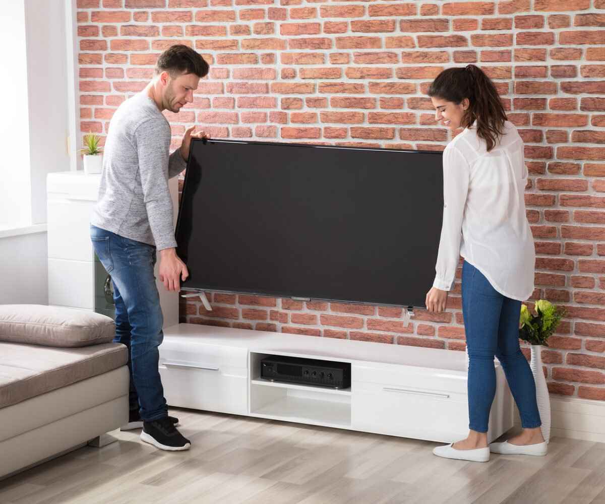 Young couple moving a television.