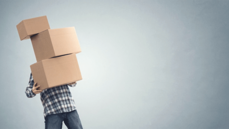 Man struggling to carry three stacked moving boxes.