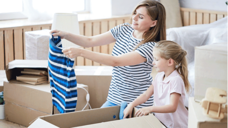 Mother and daughter filling moving boxes.