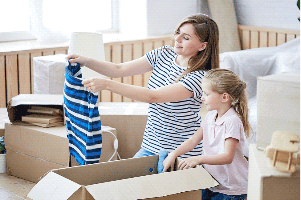 Mother and daughter filling moving boxes.