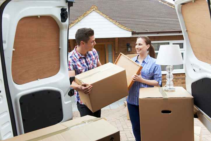 Young couples moving boxes into a van.