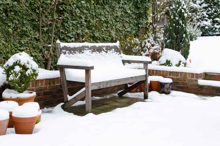 Snow covered garden bench on a patio in winter