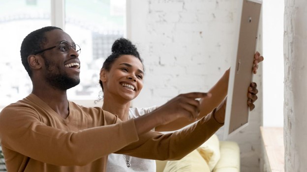 A couple hanging a photo frame together.